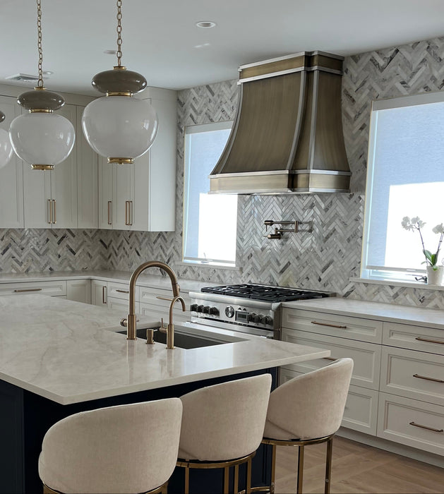 Antique brushed brass curved custom range hood with brushed stainless steel straps at rangehoodmaster