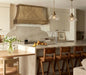 Handcrafted antique brass custom stove hood with crown molding detail in a luxury kitchen