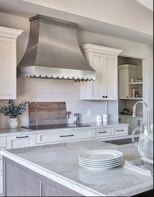 Brushed stainless steel range hood with scalloped apron and flat crown molding at rangehoodmaster