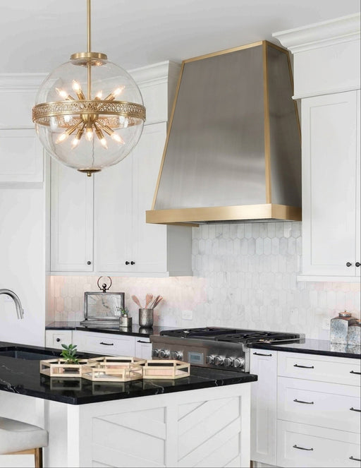 Classic tapered stainless steel custom range hood with brushed brass apron and edge trim by Range Hood Master for luxury kitchens.