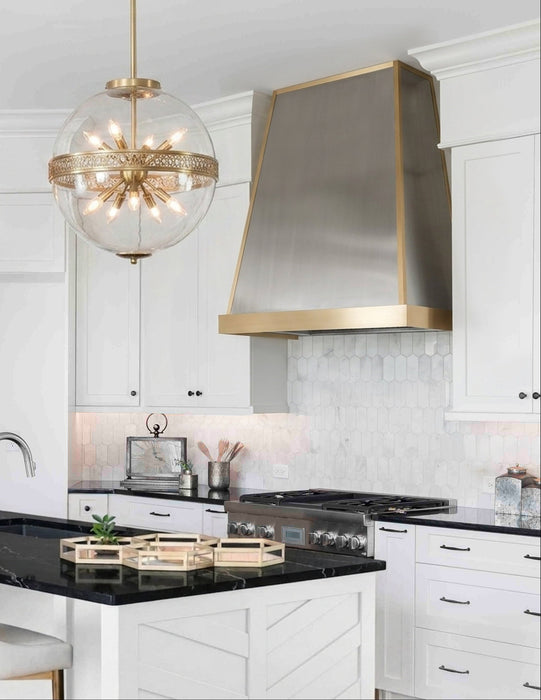 Classic tapered stainless steel custom range hood with brushed brass apron and edge trim by Range Hood Master for luxury kitchens.