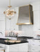 Classic tapered stainless steel custom range hood with brushed brass apron and edge trim by Range Hood Master for luxury kitchens.