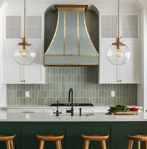 stainless steel range hood custom light green painted with brushed brass straps and rivets sleek curve shape at rangehoodmaster