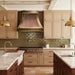 custom brushed antique copper range hood in modern curve shape with polished brass straps and rivets at rangehoodmaster