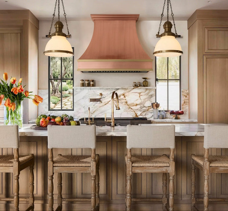 Handcrafted natural copper curved kitchen range hood with polished brass trims and crown molding at rangehoodmaster