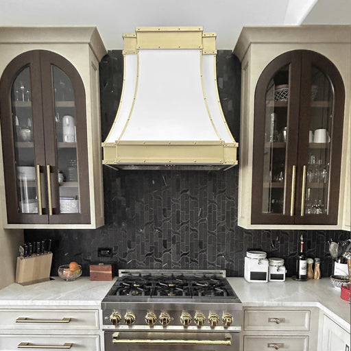 stainless steel range hood custom white painted modern curve shape with brushed brass apron and straps and rivets at RangeHoodMaster
